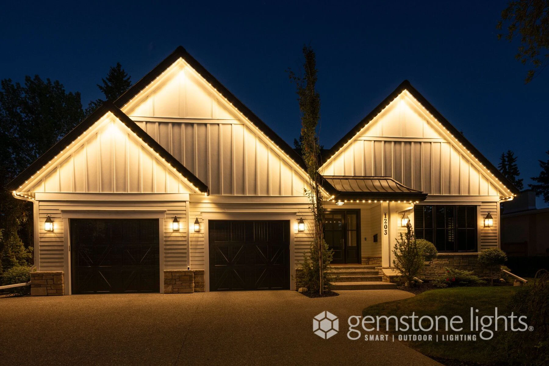 Farmhouse with warm white permanent lights along its peaks