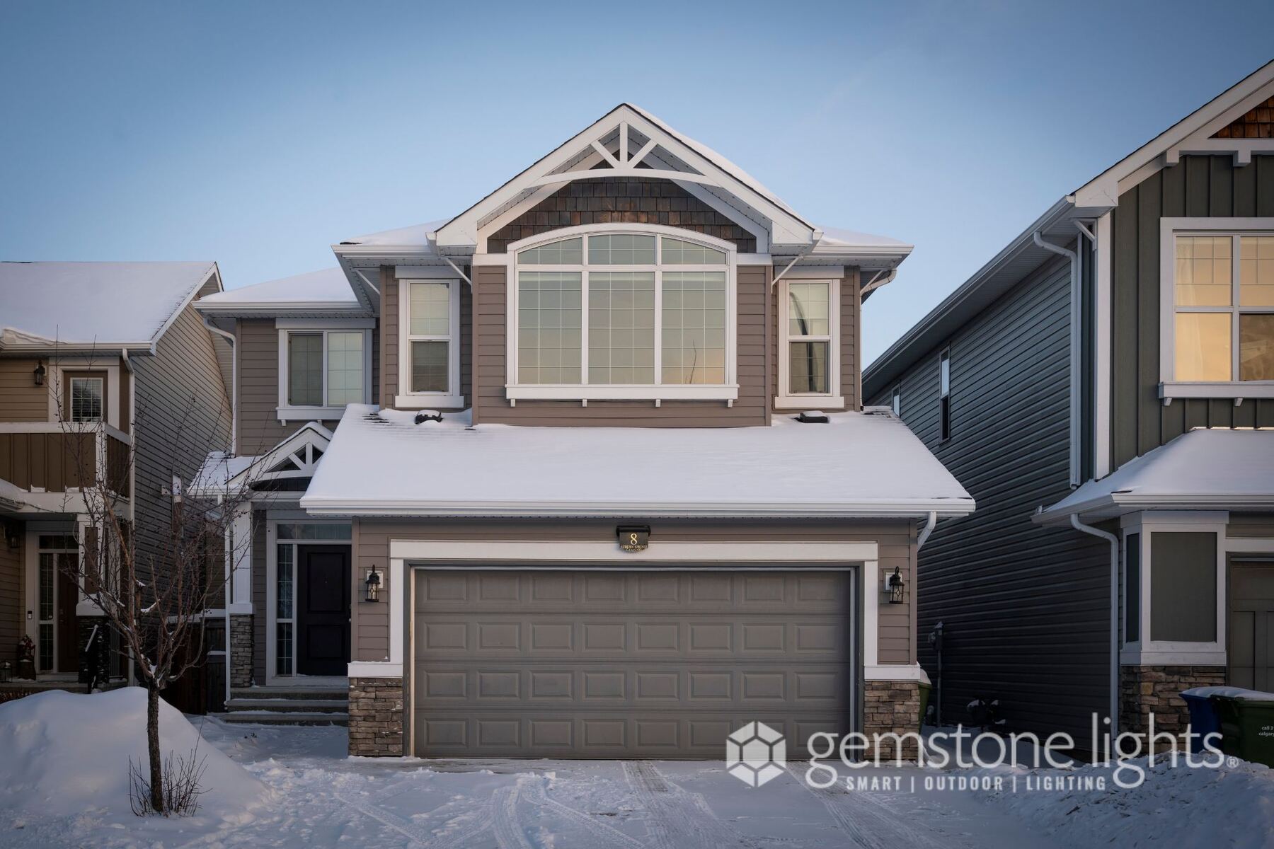 Two-story home in winter daylight with permanent lights installed but switched off